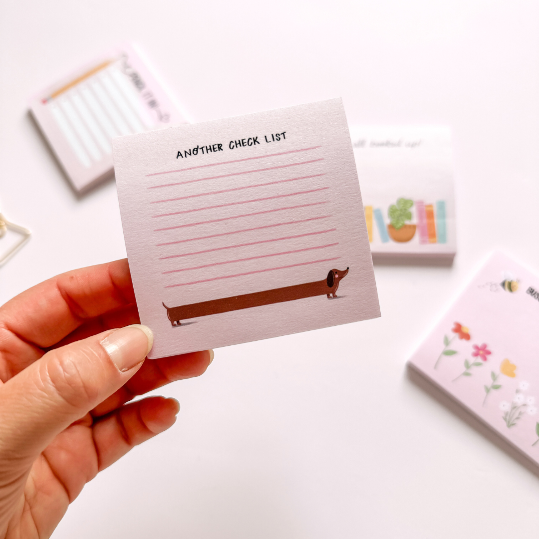 Hand-illustrated pink sticky notepad featuring a blushing dachshund and the label 'Another Check List'.