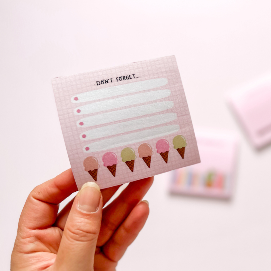 Hand-illustrated pink sticky notepad with a row of colorful ice cream cones on a checkered background, accompanied by rows of lines for writing, labeled 'Don't Forget.