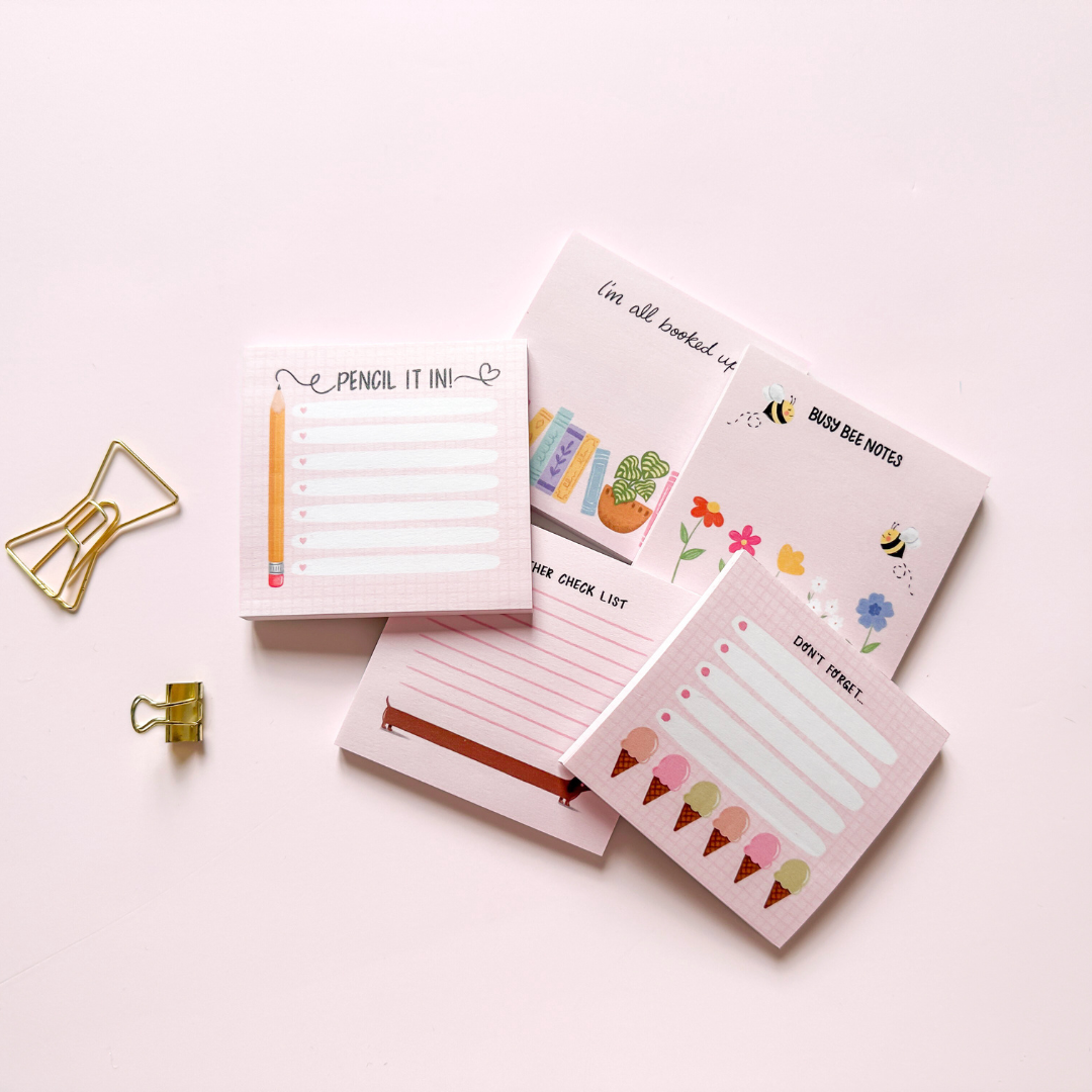 A collection of pink, femme, girly sticky note pads that feature hand illustrated designs.